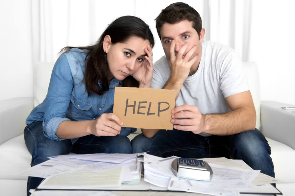Couple in debt holding up HELP sign