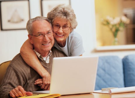 Senior couple smiling while on their laptop