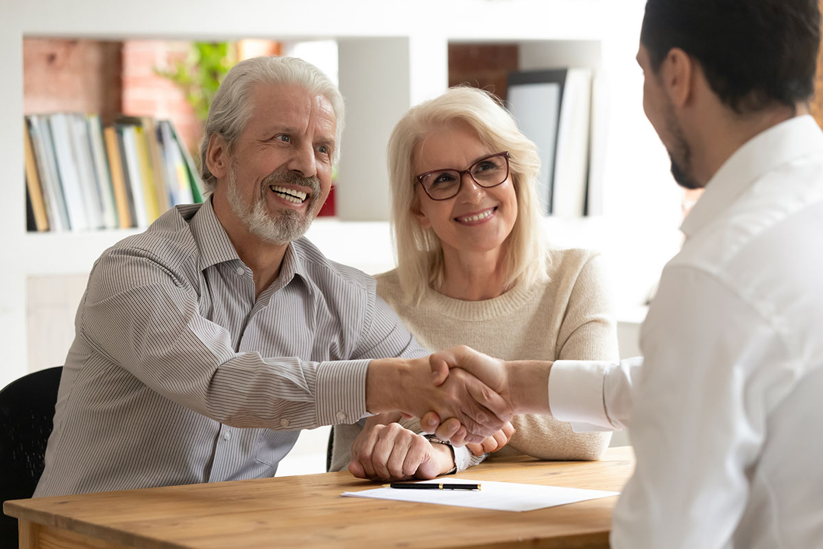 Happy seniors shaking hands with Financial Advisor